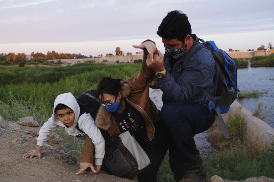 A migrant family from Brazil seeking asylum struggles up an embankment to reach the United States after crossing the dammed Colorado River from Mexico in Yuma, Ariz., in June.