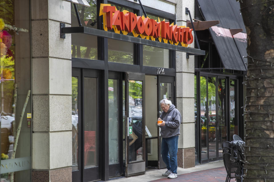 A customer checks his take out order from Tandoori Nights restaurant in Bethesda, Md., Monday, May 11, 2020. As states push for some return to normal business operations, elected officials in the Virginia and Maryland suburbs surrounding Washington, D.C., are unwilling to quickly reopen, as they confront COVID-19 infection and fatality numbers that are the highest in their states. (AP Photo/Manuel Balce Ceneta)