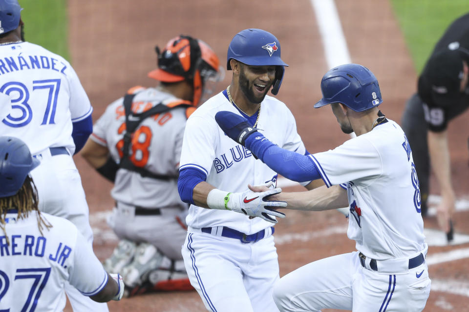 Toronto Blue Jays' Lourdes Gurriel Jr., center, celebrates with Cavan Biggio, right, after Gurriel Jr. hit a grand slam home run during the first inning of a baseball game against the Baltimore Orioles in Buffalo, N.Y., Thursday, June 24, 2021. (AP Photo/Joshua Bessex)