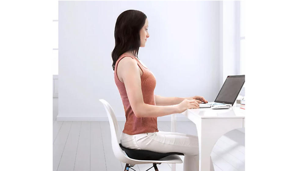 Woman sitting at the desk while using this standing seat and sitting upright