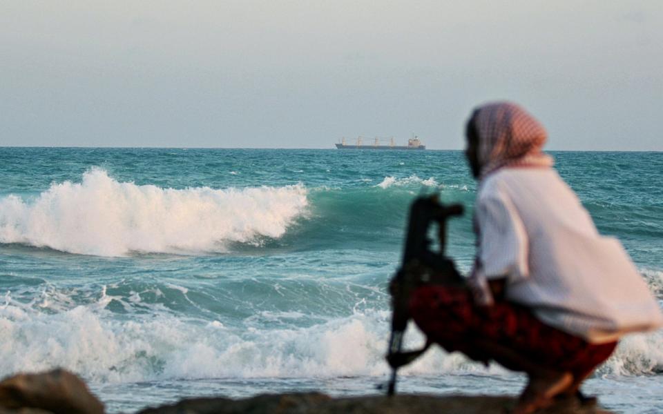 An armed Somali pirate keeps vigil on the coastline near Hobyo in 2010 - AFP