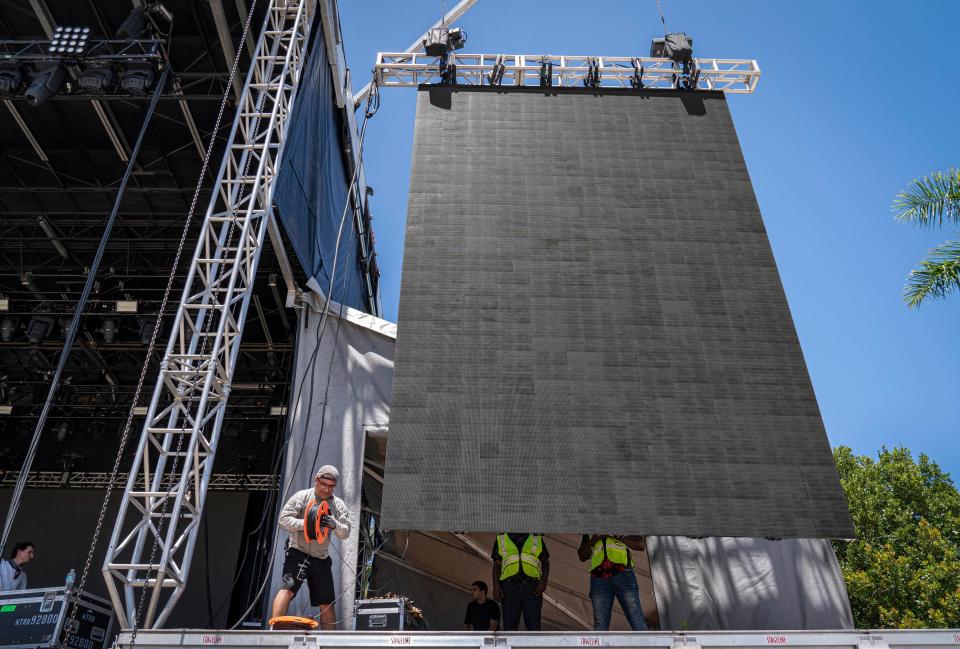 Glauco Cruz wraps up electrical wires while working on the giant monitors on the Ford stage for Sunfest Tuesday in West Palm Beach.