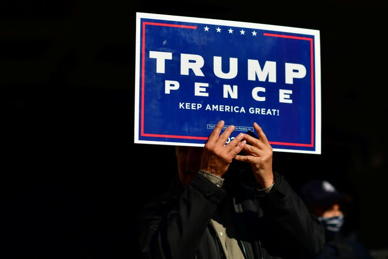 A Trump supporter clutches a campaign sign with both hands after Democratic presidential nominee Joe Biden overtook President Donald Trump in Philadelphia