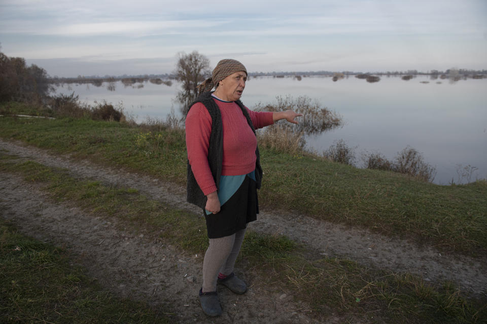 Tetyana Samoilenko, 51, walks near the flooded area in the village of Demydiv, about 40 kilometers (24 miles) north of Kyiv, Ukraine, Tuesday, Nov. 2, 2022. "I feel depressed — there's water all around and under my house," said Demydiv resident Tatiana Samoilenko. "I don't see much changing in the future." (AP Photo/Andrew Kravchenko)