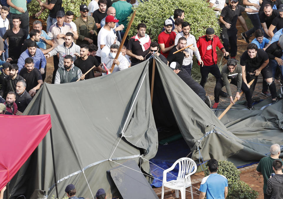 Hezbollah supporters destroy the tents of anti-government protesters, after a clashes erupted between them near the government palace, in downtown Beirut, Lebanon, Friday, Oct. 25, 2019. Hundreds of Lebanese protesters set up tents, blocking traffic in main thoroughfares and sleeping in public squares on Friday to enforce a civil disobedience campaign and keep up the pressure on the government to step down. (AP Photo/Hussein Malla)