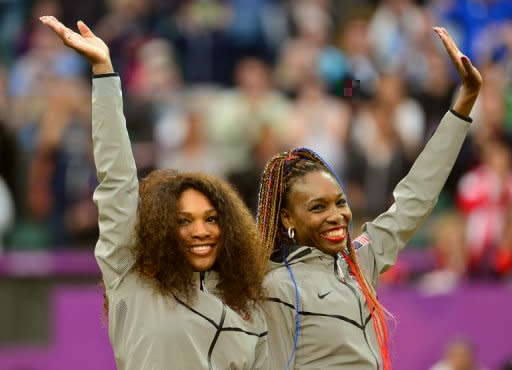 US Serena Williams (L) and Venus Williams celebrate on the podium after receiving their gold medals for winning the London 2012 Olympic Games women's doubles tennis tournament, at the All England Tennis Club in Wimbledon, southwest London