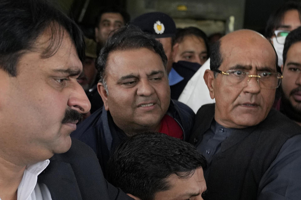 Plainclothes police officials escort Fawad Chaudhry, center, a senior leader of former Prime Minister Imran Khan's party, after his medial checkup at a hospital in Lahore, Pakistan, Wednesday, Jan. 25, 2023. Police in Pakistan arrested a senior leader of former Prime Minister Imran Khan's party on charges of threatening the chief of the elections overseeing body and other government officials. (AP Photo/K.M. Chaudary)