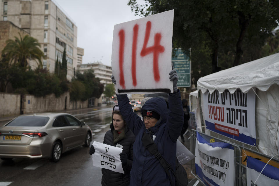 Jennifer Gamulka holds up a sign in reference to the 114 days that hostages have been held in the Gaza Strip after the cross-border attack by Hamas on Oct. 7, as she stands with her daughter Eliana on a street in Jerusalem, Israel, Sunday, Jan. 28, 2024. (AP Photo/Leo Correa)