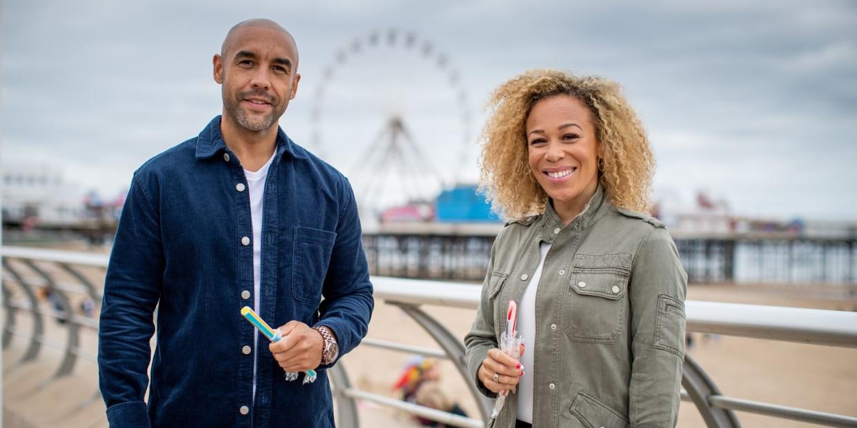 all about britain, alex beresford and rita hebden at the seaside holding sticks of rock