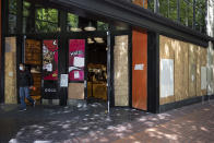 A man walks out of the Nike store which is protected by wooden panels to prevent windows being broken by on-going protests in downtown Portland, Ore., on Saturday, June 5, 2021. City officials insist Portland is resilient as they launch a revitalization plan — in the form of citywide cleanups of protest damage, aggressive encampment removals, increased homeless services and police reform — to repair its reputation. (AP Photo/Paula Bronstein)