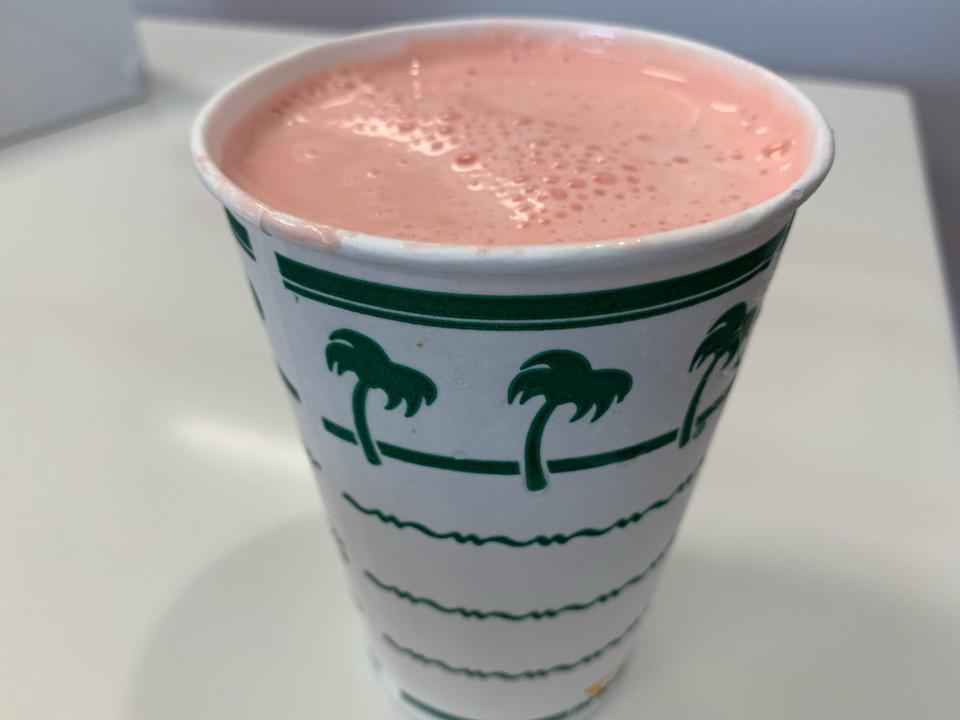 In-n-out strawberry shake in a white-and-green cup on a white table