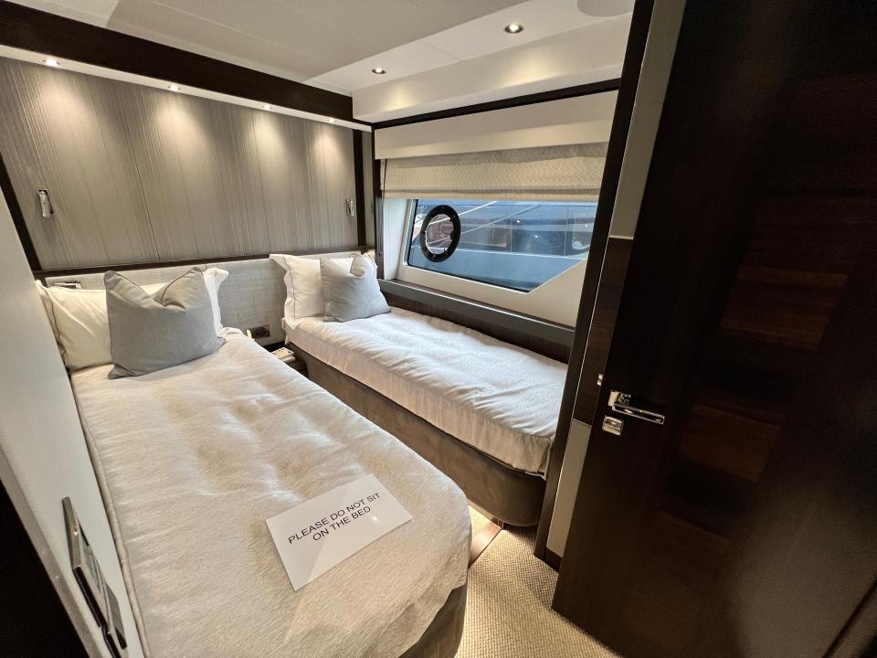 Two narrow twin beds side-by-side in the guest cabin of a Sunseeker 76 Yacht, with grey walls and linen.