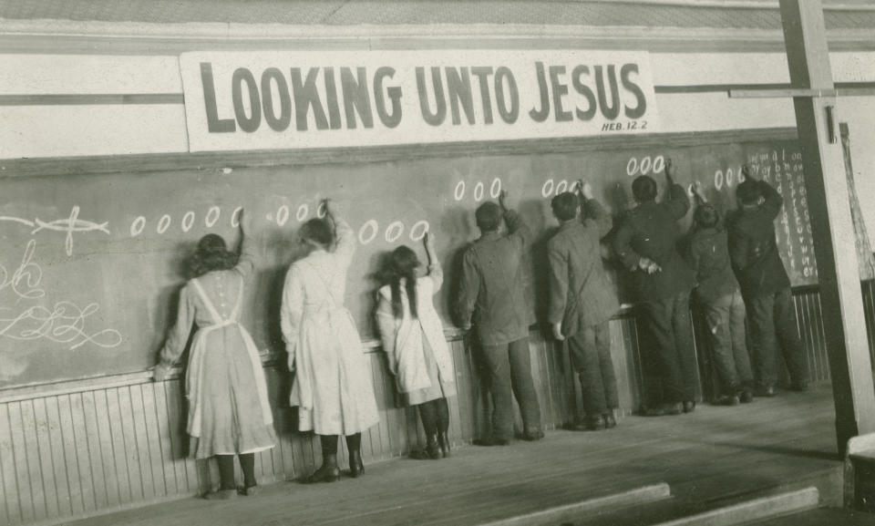 In this 1910s photo provided by the United Church of Canada Archives, students write on a chalkboard at the Red Deer Indian Industrial School in Alberta. In Canada, where more than 150,000 Indigenous children attended residential schools over more than a century, a National Truth and Reconciliation Commission identified 3,201 deaths amid poor conditions. (United Church of Canada Archives via AP)