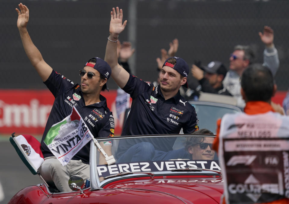 Red Bull driver Sergio Perez, of Mexico, left, and teammate Max Verstappen, of the Netherlands, wave to the crowd during the parade prior to the Formula One Mexico Grand Prix auto race at the Hermanos Rodriguez racetrack in Mexico City, Sunday, Oct. 30, 2022. (AP Photo/Fernando Llano)