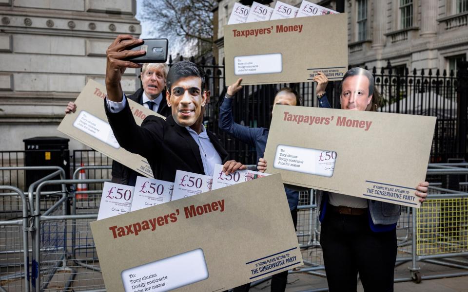 Labour Party campaigners pose for a selfie outside Downing Street during a stunt in which they carried envelopes labelled 'Taxpayer's Money' - Getty