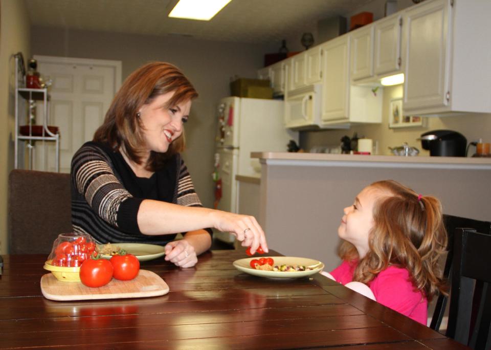 This Jan. 21, 2014 photo released by MediaSource shows Shannon McCormick, left, serving a tomato to her 4 year old daughter Sophie Chapman at their home in Gahanna, Ohio. Although not fond of tomatoes, McCormick keeps that fact from her daughter, who loves them. (AP Photo/MediaSource, Robert Leitch)