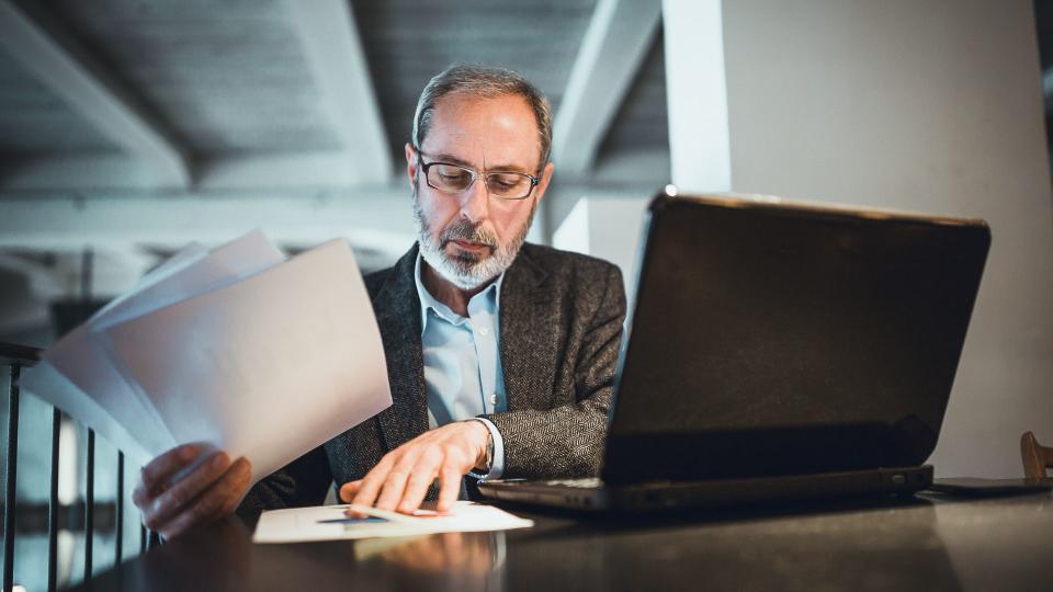 Mature male worker is using a laptop in high end restaurant.