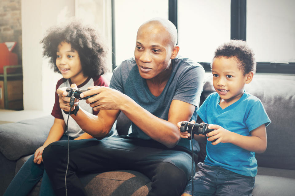 A father plays a video game with his two children.