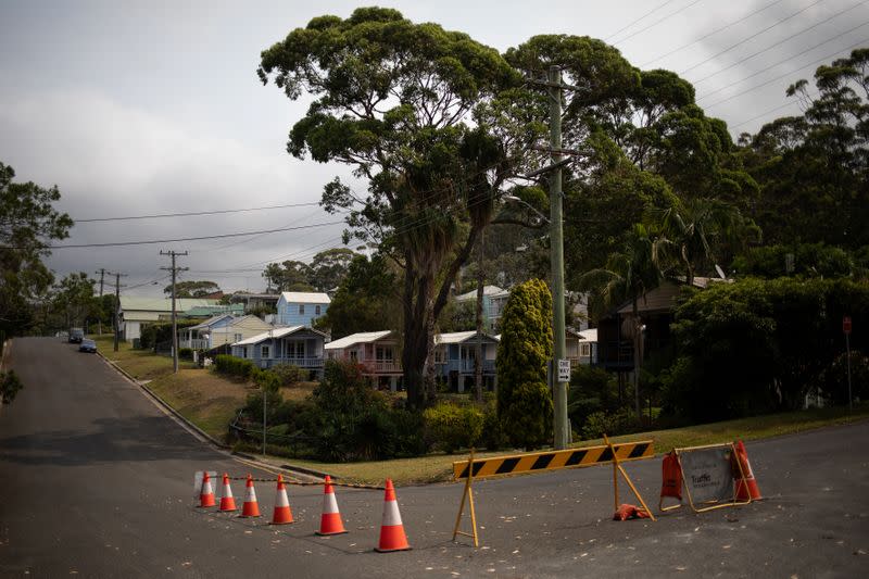 A road block is seen on a crossroad next to houses in Hyams Beach