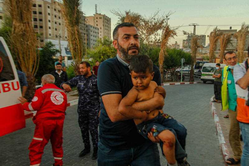 A man is seen carrying a child in his arms in Beit Lahiya, Gaza.