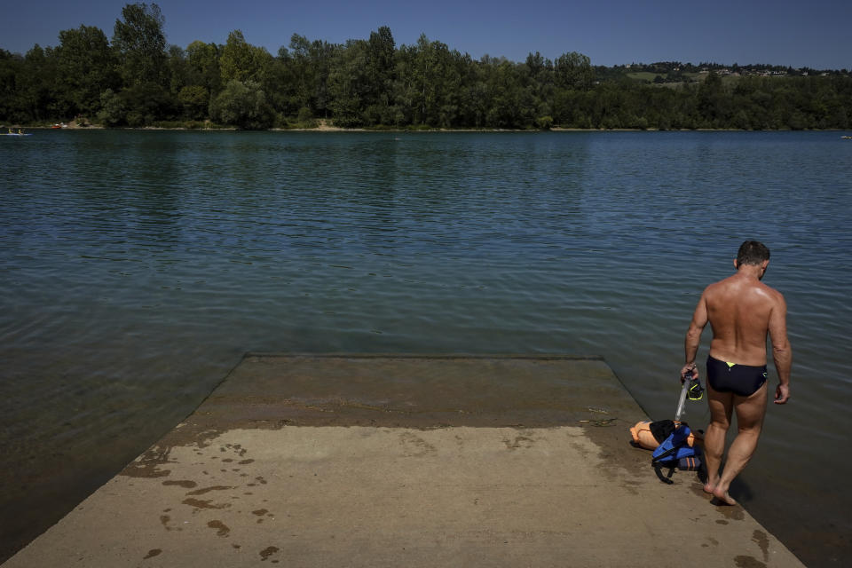 A man prepares to enter in the water during a heatwave in Anse, outside Lyon, central France, Sunday, July 17, 2022. (AP Photo/Laurent Cipriani)