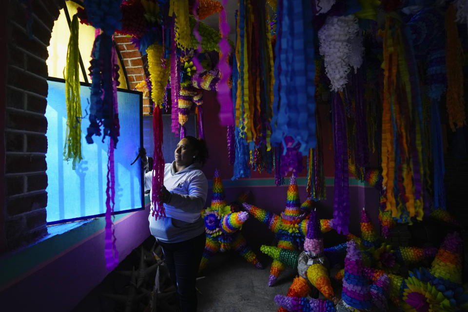 María de Lourdes Ortiz Zacarías vende piñatas en su pequeño negocio familiar en Acolman, al norte de Ciudad de México, el miércoles 13 de diciembre de 2023. La familia empezó con su local en Acolman, donde la madre de Ortiz Zacarías era conocida como "la reina de las piñatas" antes de su fallecimiento. (AP Foto/Fernando Llano)