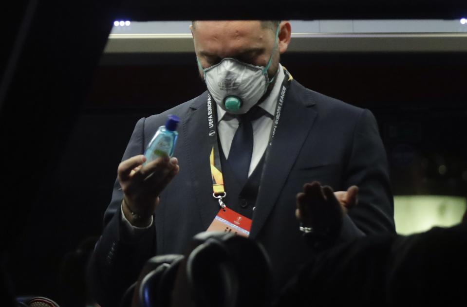 A Bulgarian soccer team Ludogorets staffer disinfects his hands on a coach bus heading to the San Siro stadium Milan, Italy, Thursday, Feb. 27, 2020. Ludogorets is playing Italian club Inter Milan in a Europa League soccer match on Thursday that is scheduled to go ahead in an empty stadium due to the coronavirus outbreak. (AP Photo/Luca Bruno)