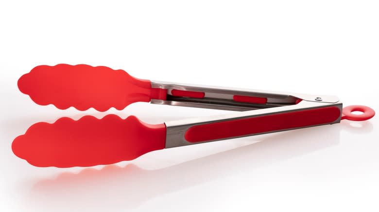 Red kitchen tongs on white background