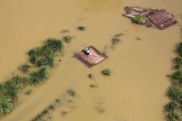 Zwei Menschen stehen auf dem Dach ihres beinahe vollständig überschwemmten Hauses in einem Außenbezirk von Allahabad in Indien. Nach den heftigen Überschwemmungen der letzten Tage warten sie auf Rettung durch einen Helikopter der indischen Luftwaffe. (Bild: Jitendra Prakash/Reuters)