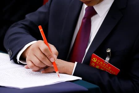 A delegate marks a passage in a text during a session on the second day of the 19th National Congress of the Communist Party of China of the Great Hall of the People in Beijing, October 19, 2017. REUTERS/Thomas Peter