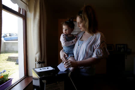 A woman holds her child as she casts her vote in Ireland's referendum on liberalizing abortion law, on Gola Island, Ireland, May 24, 2018. REUTERS/Max Rossi