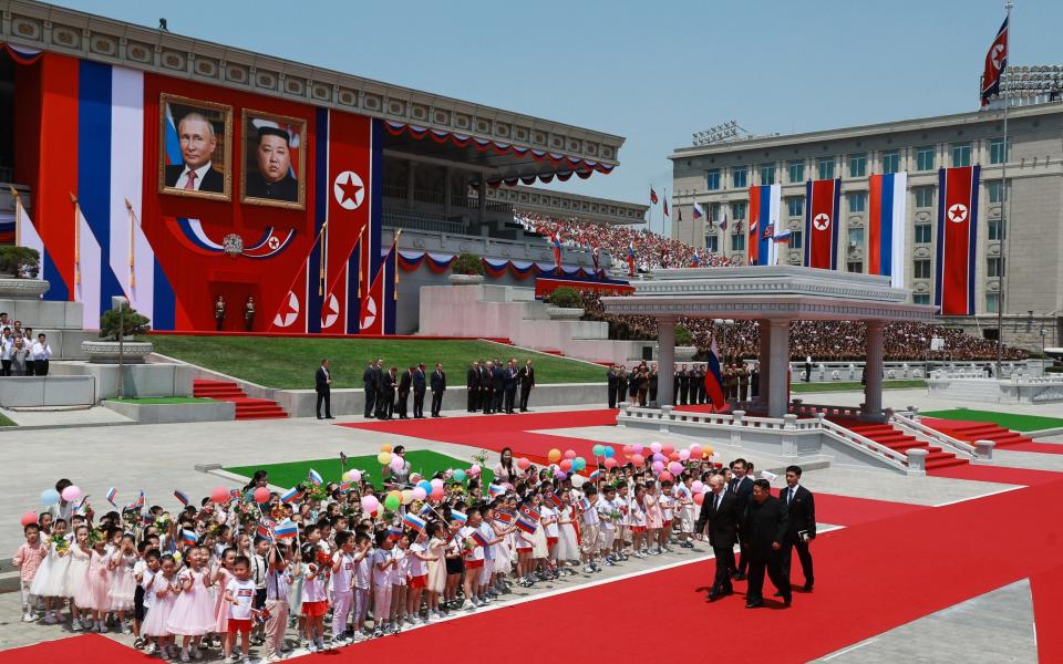 Russian state agency Sputnik, North Korea's leader Kim Jong Un (Center-R) and Russian President Vladimir Putin (L) walk past children attend a welcoming ceremony at Kim Il Sung Square