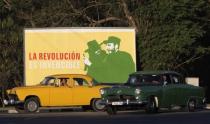 Vintage cars drive near a banner with image of Cuban late rebel revolutionary Camilo Cienfuegos (L) and Cuba's former president Fidel Castro in Havana December 23, 2014. REUTERS/Stringer