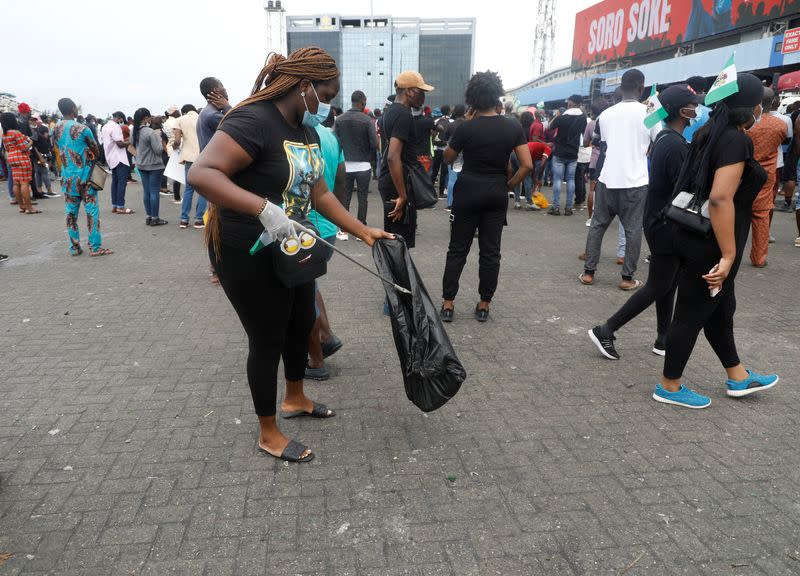 A demonstrator picks up litter from the street during a protest over police brutality in Lagos