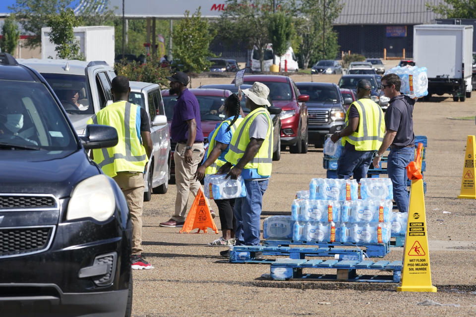 Workers at the Highway 18 Walmart distribute the last of 6,000 cases of water to long line of residents in Jackson, Miss., Thursday, Sept. 1, 2022, after a flood worsened the city's longstanding water system problems. (Steve Helber/AP)