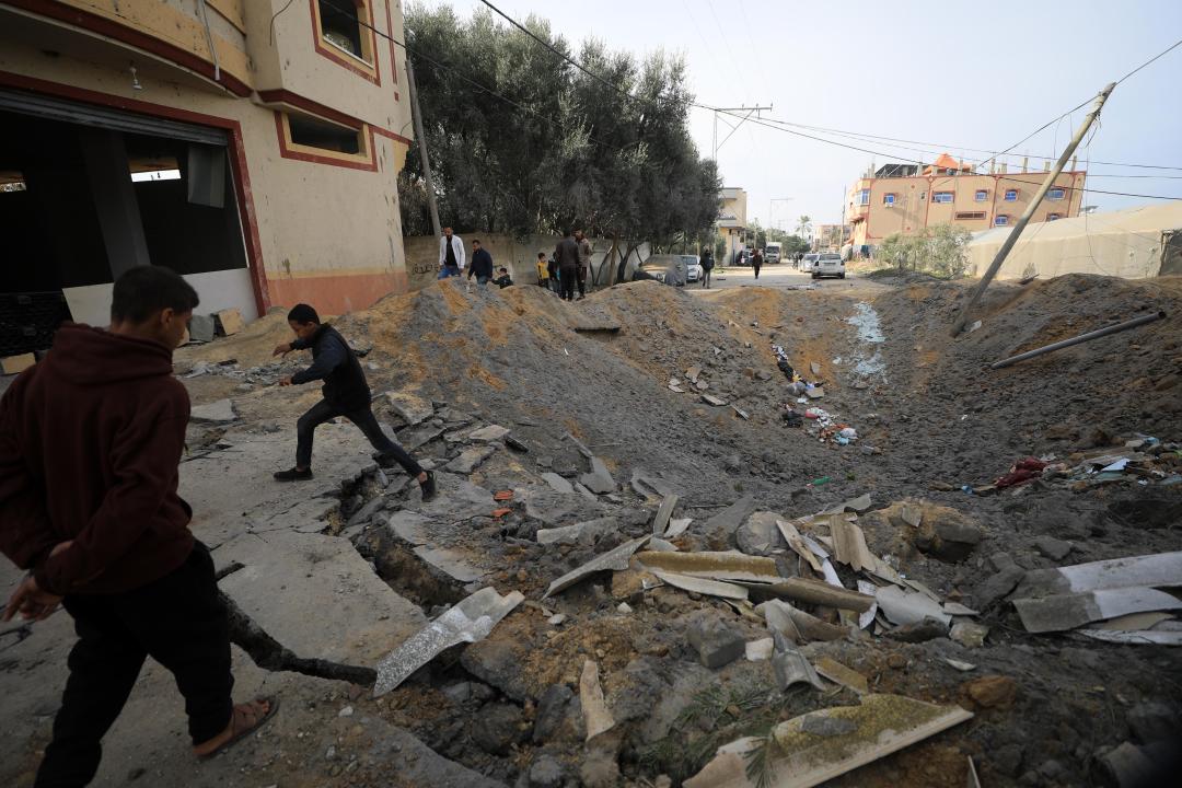 RAFAH, GAZA - FEBRUARY 12: A view of the pothole formed as a result of Israeli attack at the street as buildings heavily damage after Israeli attacks in Rafah, Gaza on February 12, 2024. Building targeted in the Israeli attacks and surrounding structures were damaged as Israel's air, land and sea attacks continue on the Gaza Strip. (Photo by Yasser Qudih/Anadolu via Getty Images)