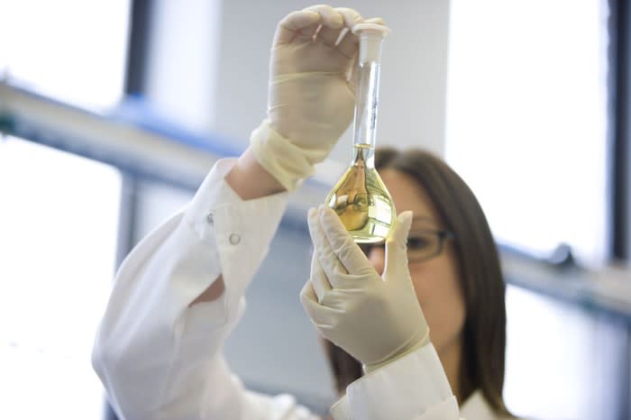 A GW Pharmaceutical lab research examining a cannabinoid-rich liquid solution in a beaker.