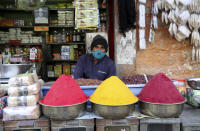 A shopkeeper wears a face mask as a precaution against the coronavirus waits for customers at a market in Bengaluru, India, Friday, Nov. 20, 2020. India's total number of coronavirus cases since the pandemic began has crossed 9 million. Nevertheless the country's new daily cases have seen a steady decline for weeks now and the total number of cases represents 0.6% of India's 1.3 billion population. (AP Photo/Aijaz Rahi)