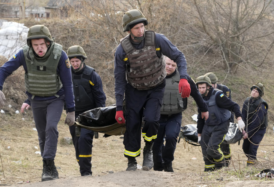 Ukrainian soldiers carry bodies of civilians killed by the Russian forces over the destroyed bridge in Irpin close to Kyiv, Ukraine, Thursday, March 31, 2022. The more than month-old war has killed thousands and driven more than 10 million Ukrainians from their homes including almost 4 million from their country. (AP Photo/Efrem Lukatsky)