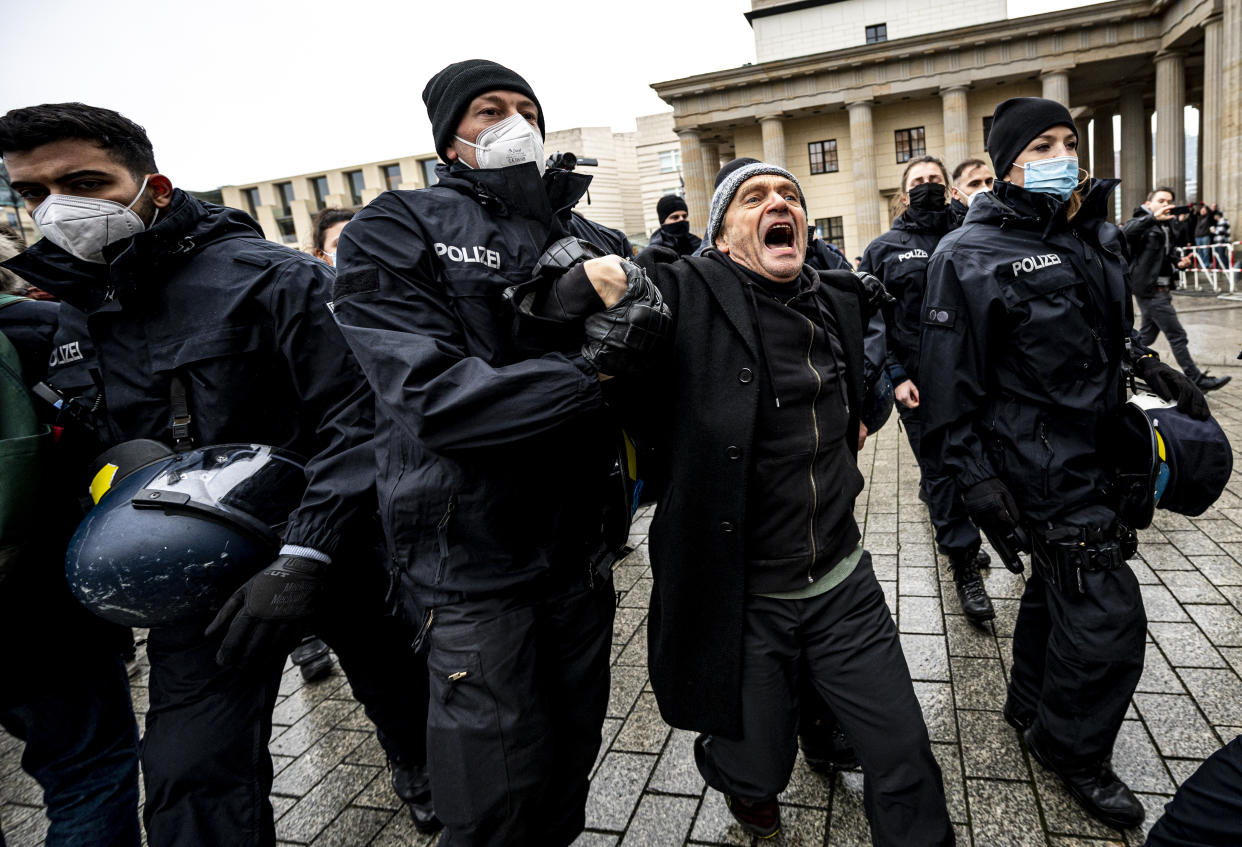 The Berlin police takes away a participant of the forbidden demonstration of opponents of Corona rules in Berlin, Germany, Saturday, Dec. 18, 2021. The demonstration had been banned by the Berlin police. (Fabian Sommer/dpa via AP)