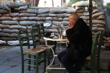 A man sits in a coffee shop in front of a barrier of sandbags at the UN-controlled buffer zone in Nicosia, Cyprus, January 11, 2017. REUTERS/Yiannis Kourtoglou