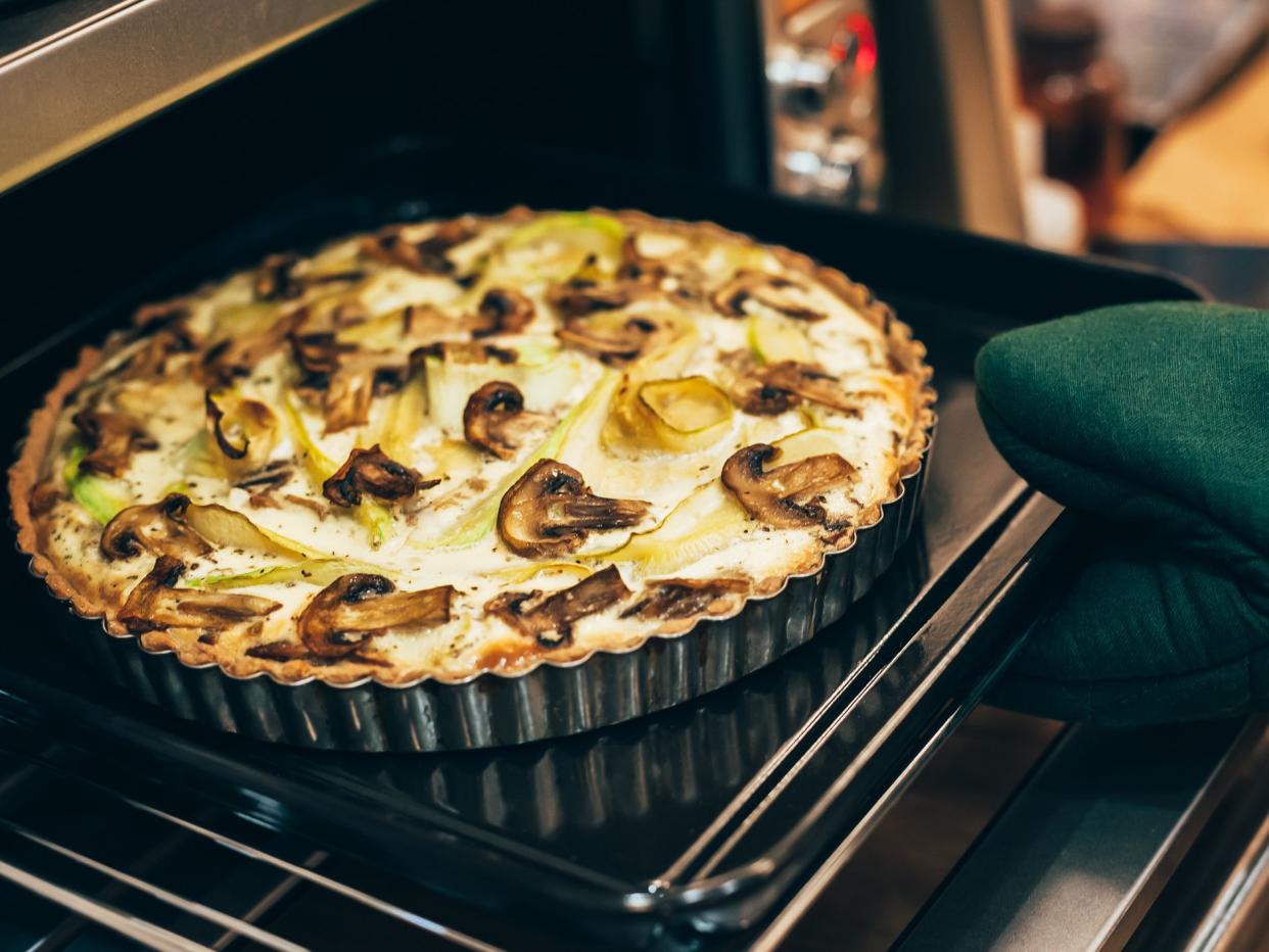 Homemade healthy gluten free vegan quiche pie with mushrooms and squash baking in hot oven for autumn holiday dining. Cozy home mood. Diet food cooking