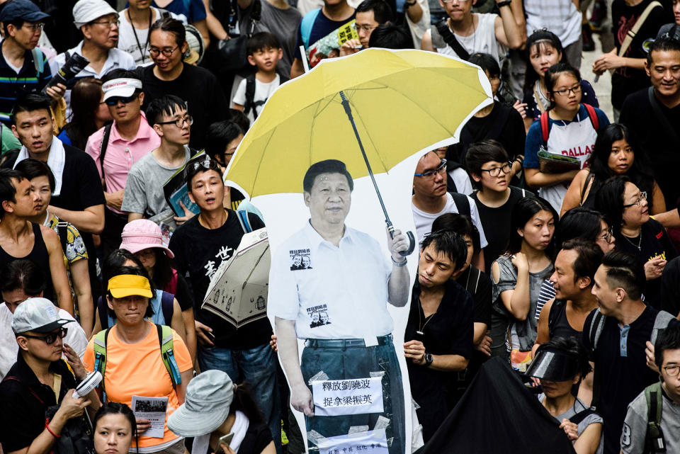 <p>A cardboard cut-out of China’s President Xi Jinping (C) holding a yellow umbrella, a symbol of the 2014 ‘Umbrella Movement’, is carried during a protest march in Hong Kong on July 1, 2017, coinciding with the 20th anniversary of the city’s handover from British to Chinese rule. (Photo: Anthony WallaceAFP/Getty Images) </p>