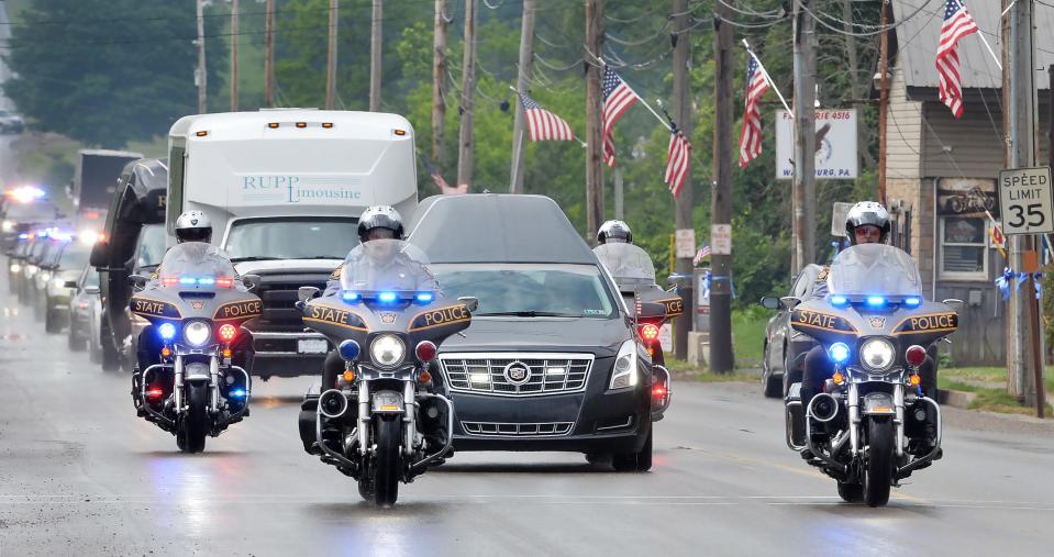 The funeral procession for Jacques "Jay" F. Rougeau Jr., a Pennsylvania State Police trooper who was fatally shot while on duty in central Pennsylvania, passes north through Wattsburg, Pa., on Monday. Viewing and the funeral for Rougeau will take place at the Bayfront Convention Center in Erie.