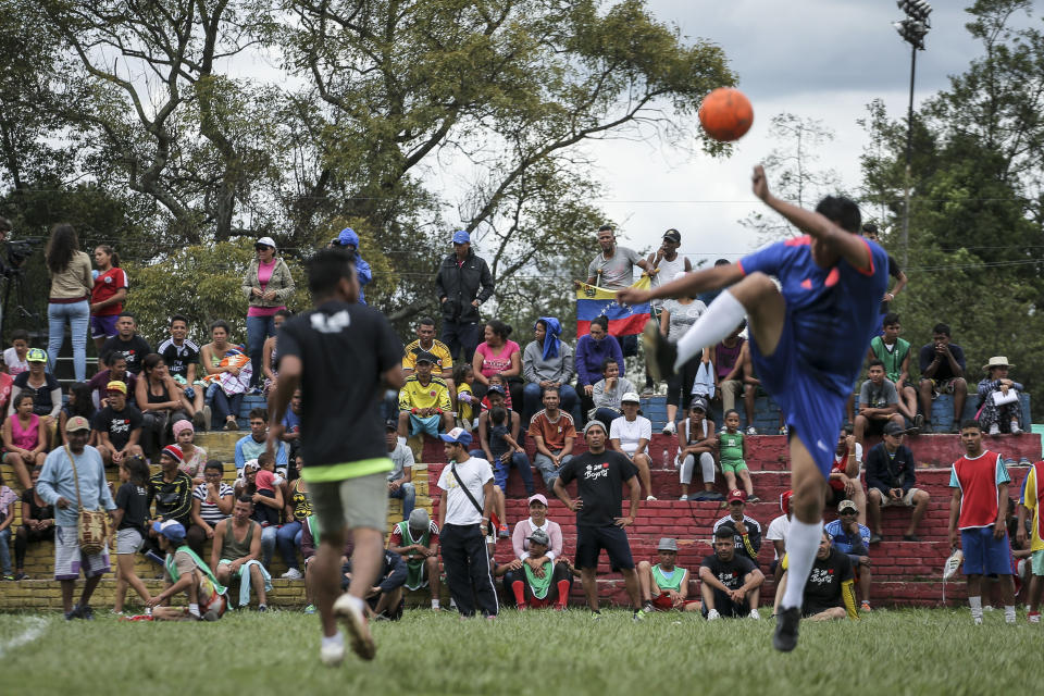 Venezuelan migrants watch and play soccer at a temporary camp in Bogota, Colombia, Wednesday, Nov. 21, 2018. City officials organized a soccer tournament for migrants living at the camp built by the city's social welfare agency to accommodate migrants who had previously been living in tents made of plastic sheets and scrap materials outside the city's bus terminal. (AP Photo/Ivan Valencia)