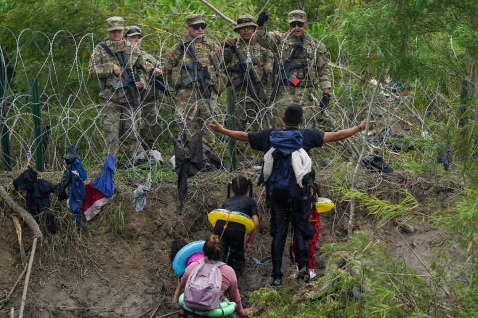 Un migrante hace un gesto a Guardias Nacionales de Texas que están detrás de una alambrada en la orilla del río Grande, visto desde Matamoros, México, el jueves 11 de mayo de 2023. Las restricciones de asilo en EEUU relacionadas con la pandemia, conocidas como Título 42, expiraron el 11 de mayo (AP Photo/Fernando Llano).