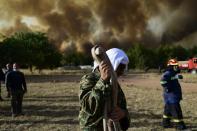 A man holds a water hose during a wildfire in Kryoneri area, northern Athens, Greece, Thursday, Aug. 5, 2021. Wildfires rekindled outside Athens and forced more evacuations around southern Greece Thursday as weather conditions worsened and firefighters in a round-the-clock battle stopped the flames just outside the birthplace of the ancient Olympics. (AP Photo/Michael Varaklas)