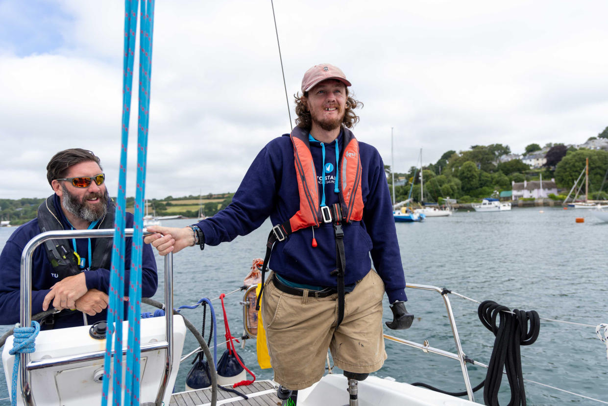 Craig Wood standing on his sailing boat wearing a life jacket and smiling 
