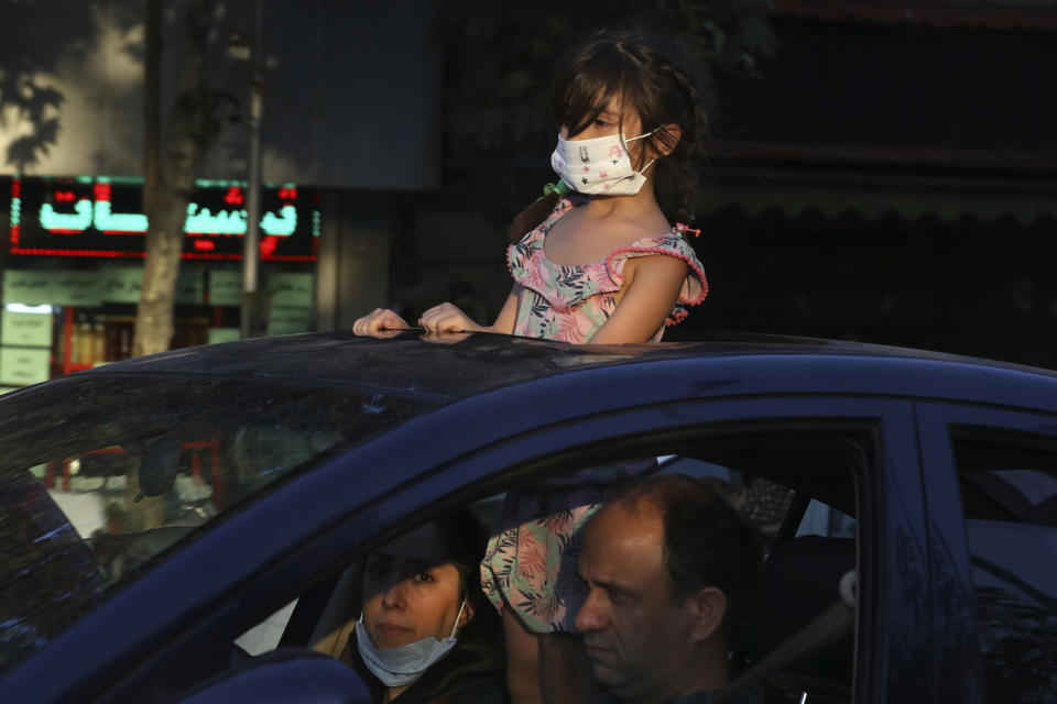 A girl wearing a protective face mask to help prevent the spread of the coronavirus looks through the sunroof of her family car on a street in central Tehran, Iran, Sunday, Aug. 8, 2021. Iranians are suffering through yet another surge in the coronavirus pandemic — their country's worst yet — and anger is growing at images of vaccinated Westerners without face masks on the internet or on TV while they remain unable to get the shots. (AP Photo/Vahid Salemi)