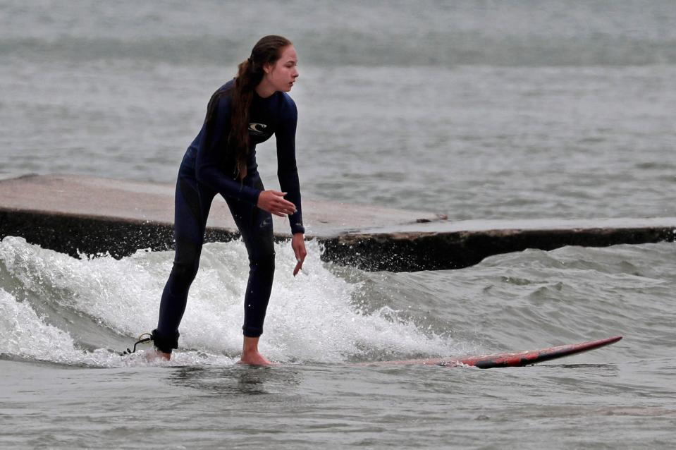 Gabi Locascio, 16, of Palos Park, Illinois glides near a jetty near Deland Park, Wednesday, August 11, 2021, in Sheboygan, Wis.  She was visiting relatives in Sheboygan and got some surfing in.